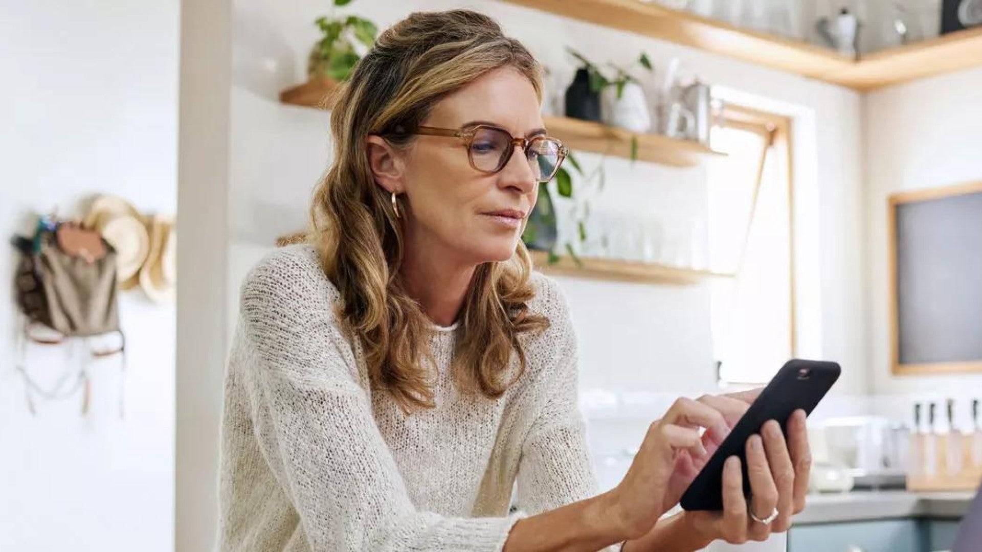  Una mujer mirando similitudes y diferencias entre una cuenta IRA y una cuenta 401(k) en su teléfono.