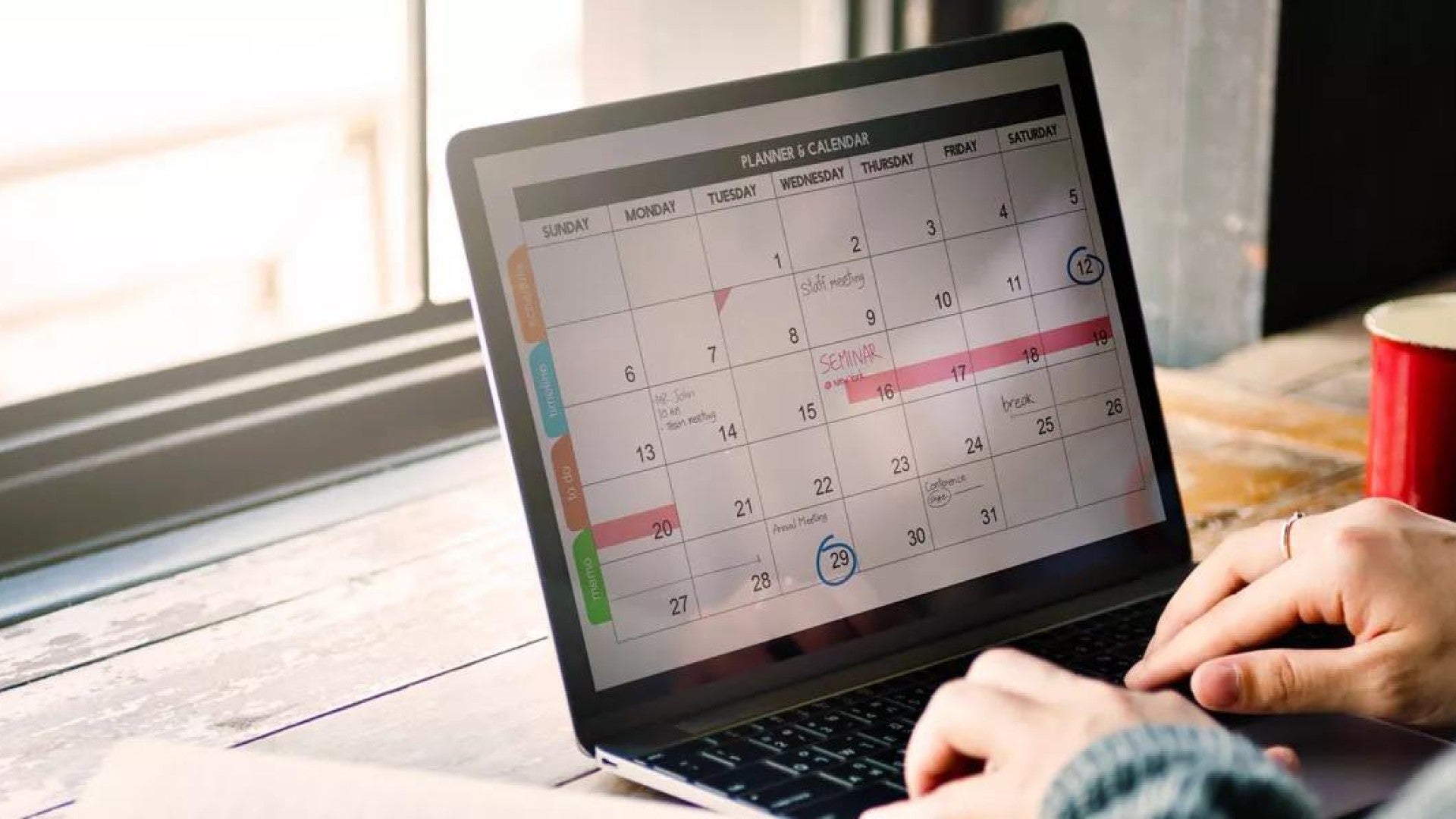 A woman at her laptop entering key financial dates for the year.