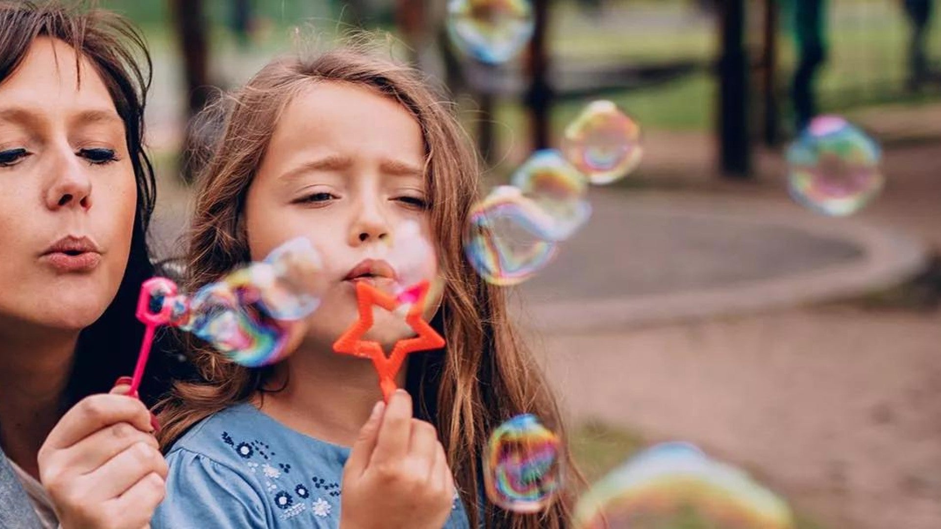 Mom and daughter blowing bubbles at the park