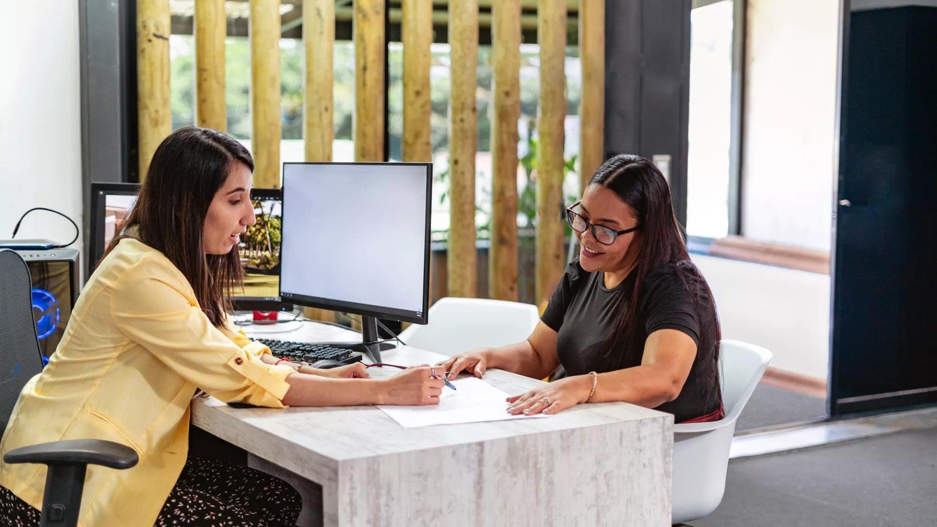 Business decision maker reviewing paperwork with an employee across a desk.