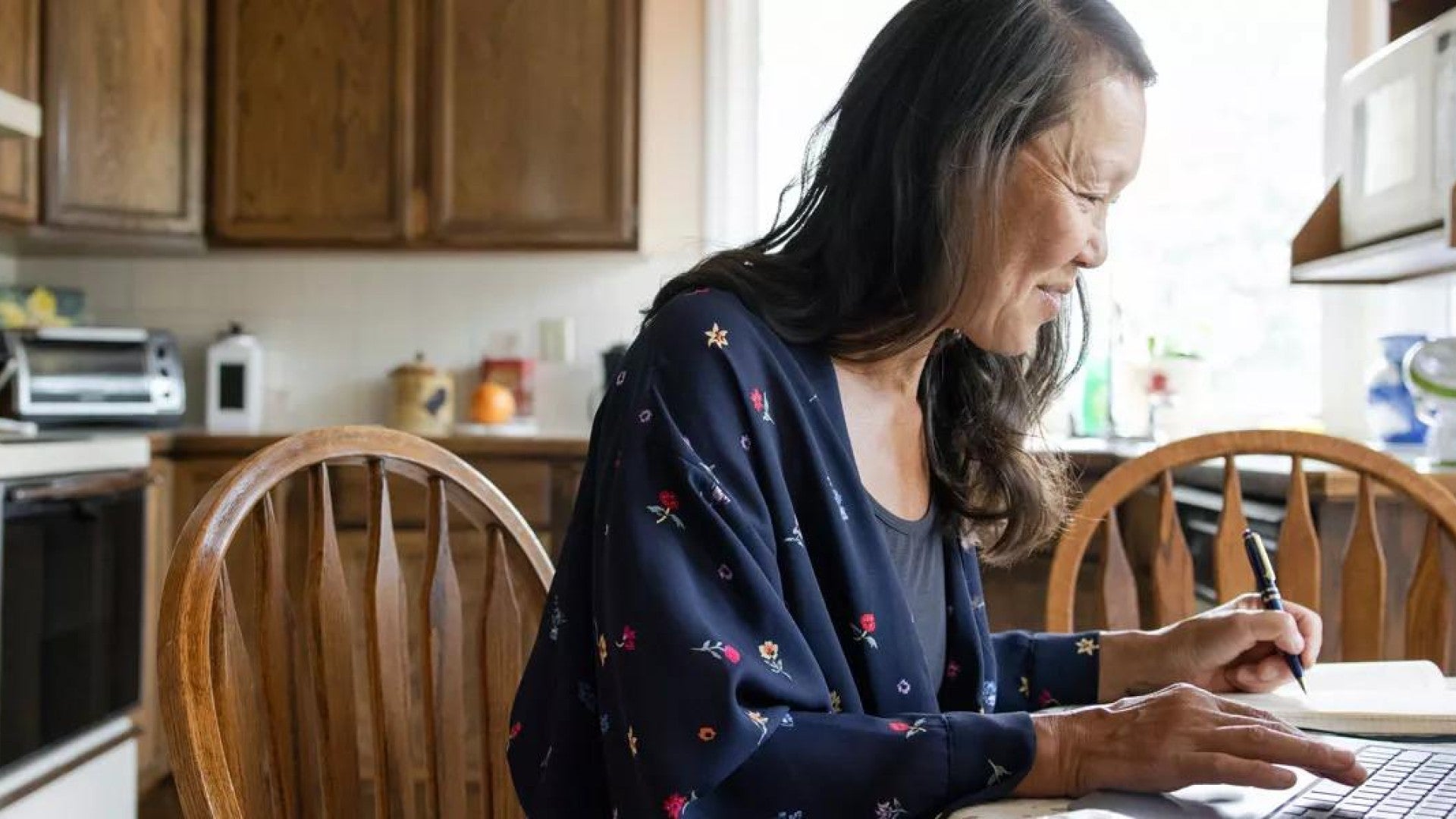 Woman working from home at laptop in kitchen