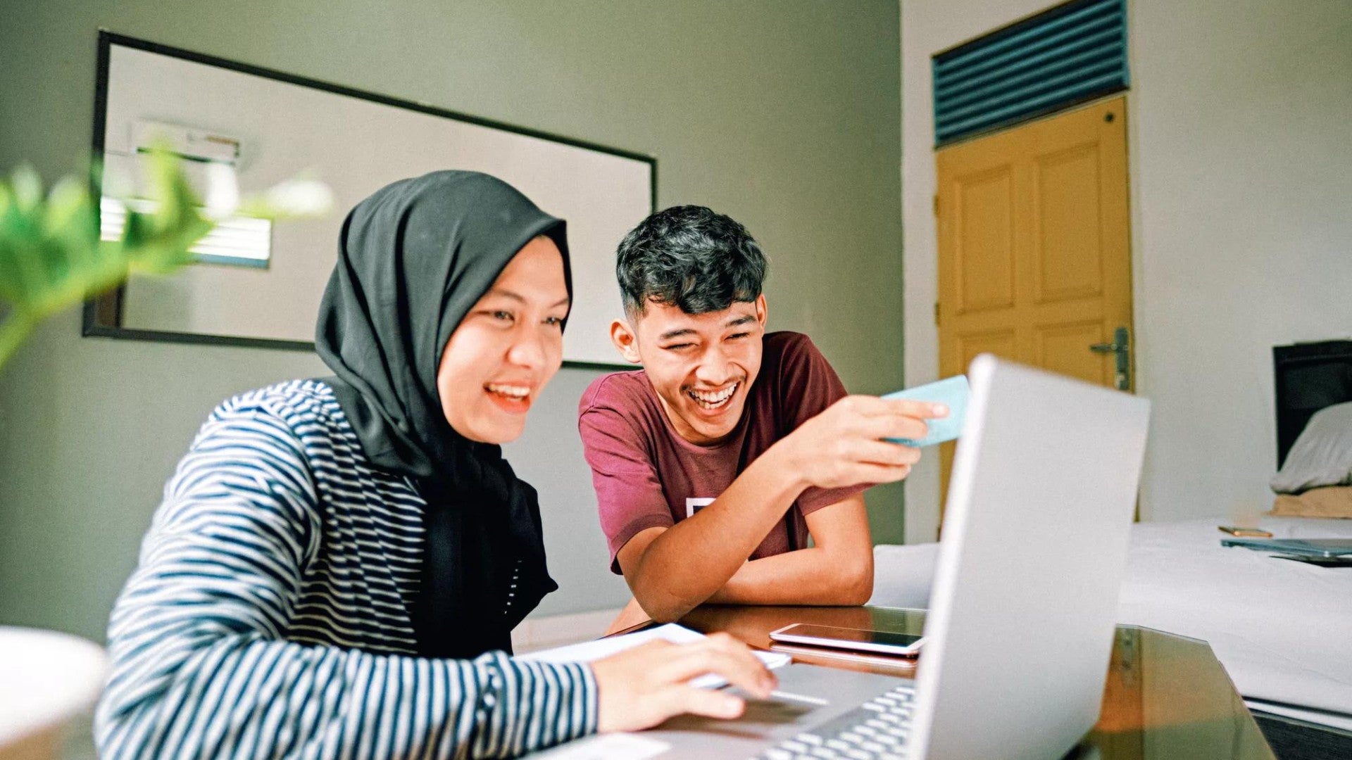 Asian couple looking at their laptop together.