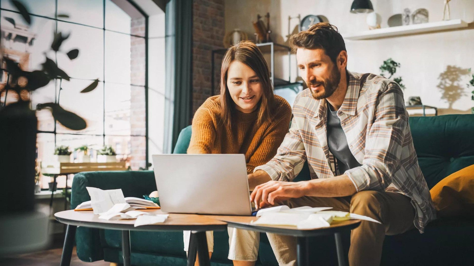 Hombre y mujer sentados en un sofá mirando las condiciones de inversión en una computadora portátil.