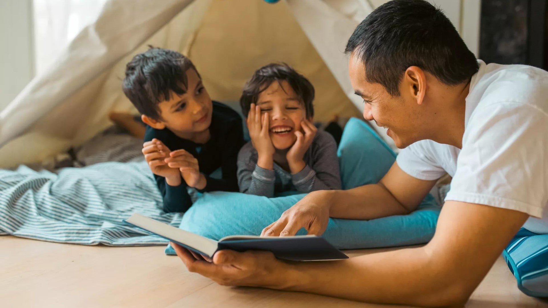 A father reads to his two children and will be sure to look after their needs in his will and estate plan.