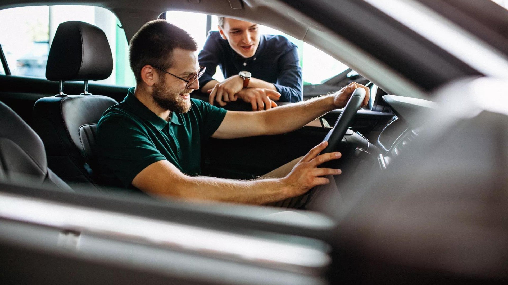 Young man testing new car at a showroom