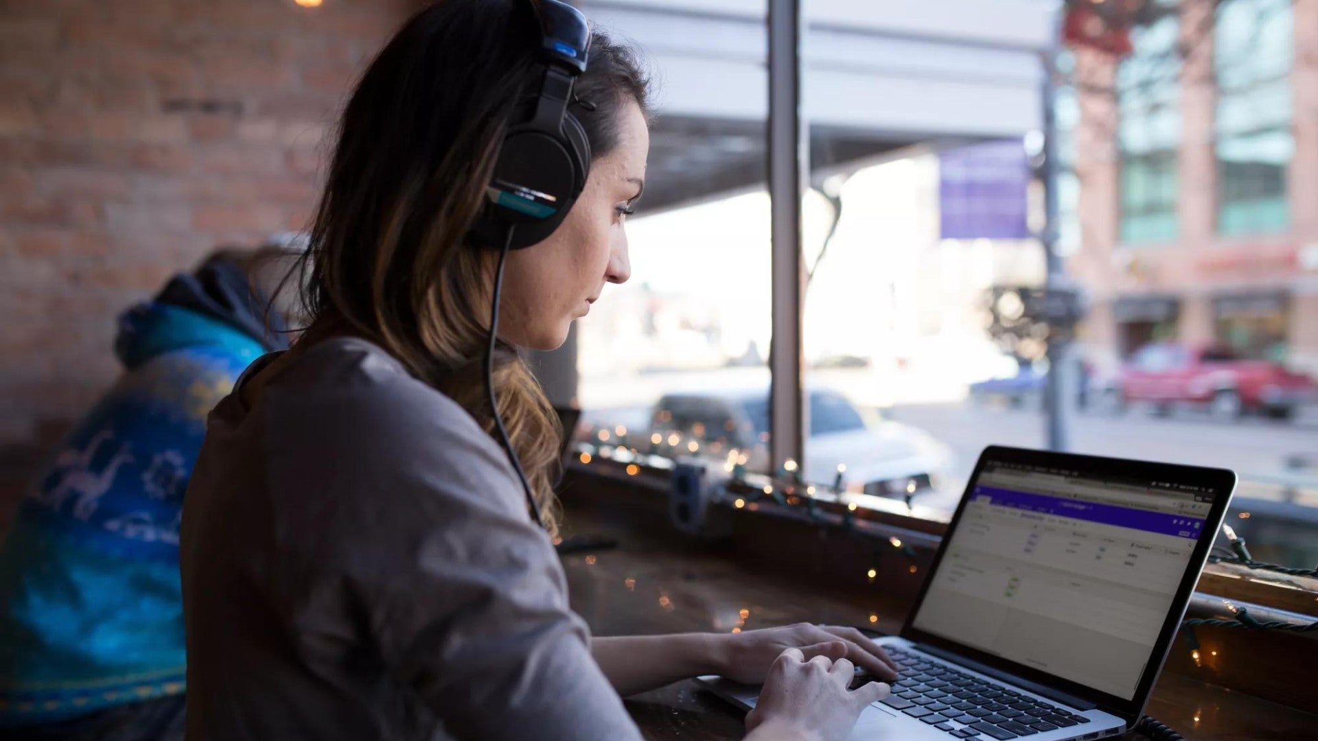 Woman working remotely on laptop at coffee shop counter.