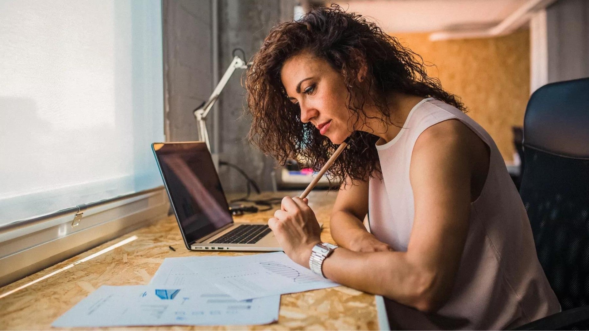 Woman sitting at a desk working on her retirement plan on paper and a computer