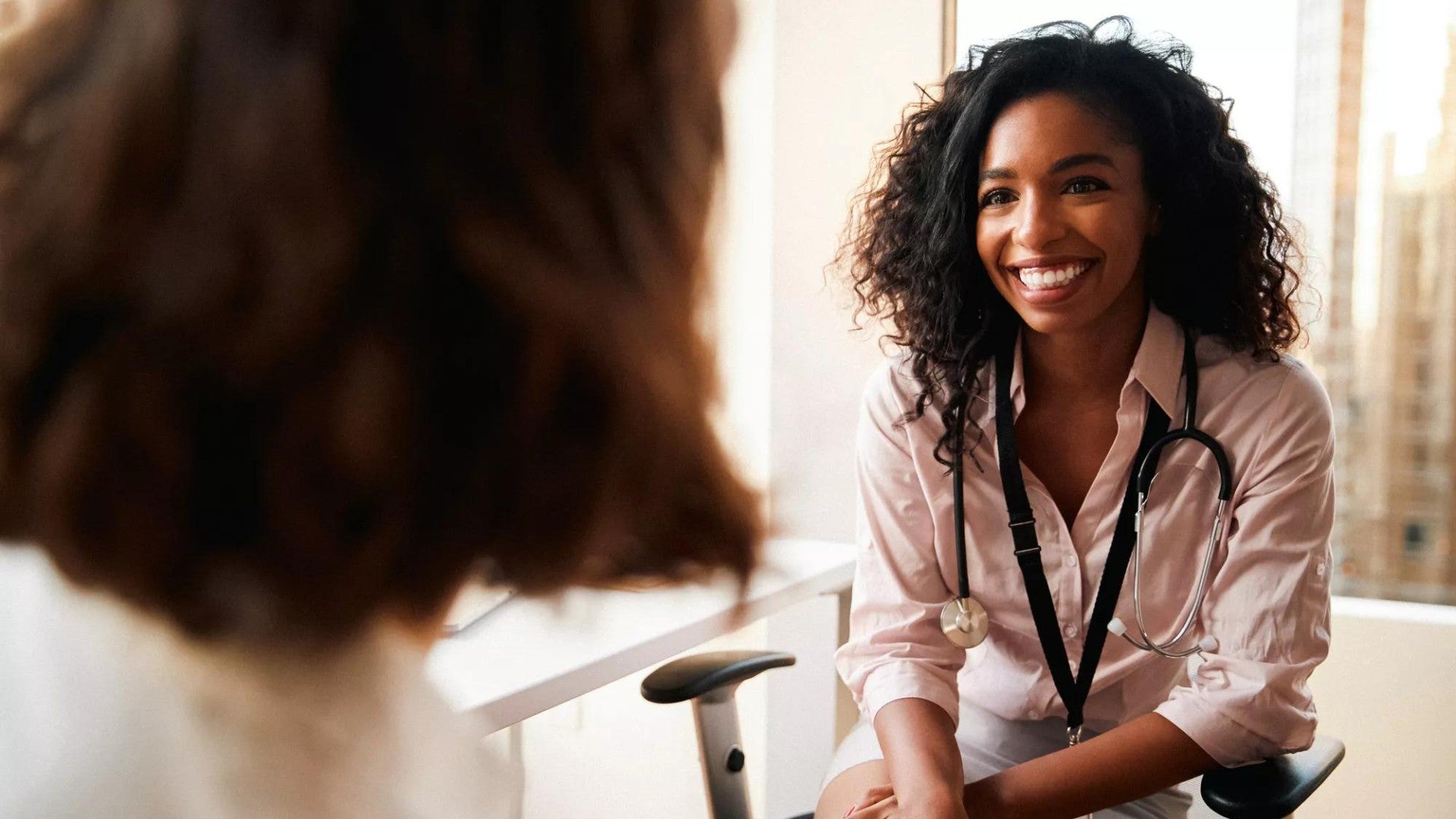 Woman having consultation with female doctor in hospital office.