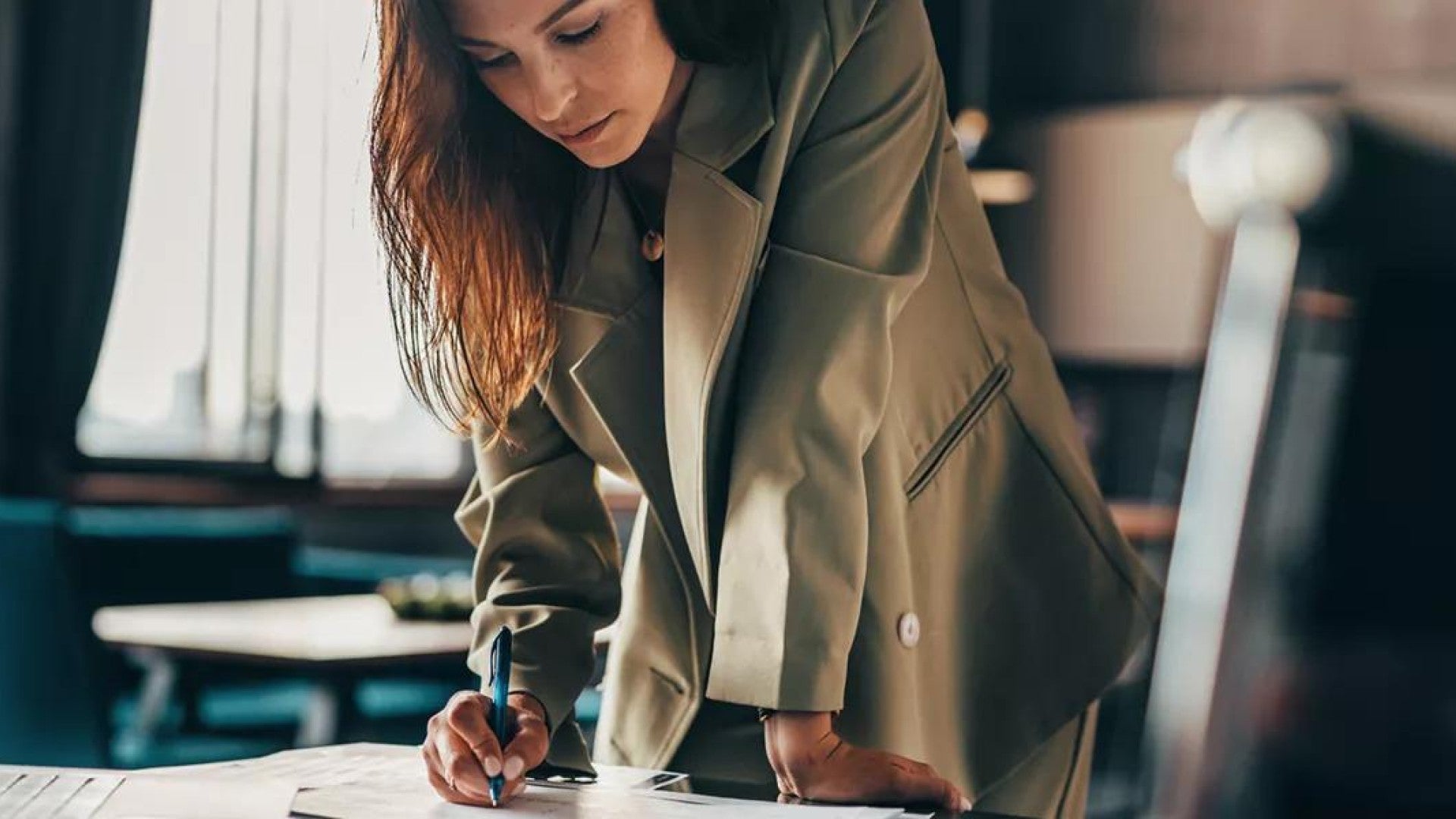 Photo of a woman leaning over a table and reviewing documents related to her investments due to market volatility.
