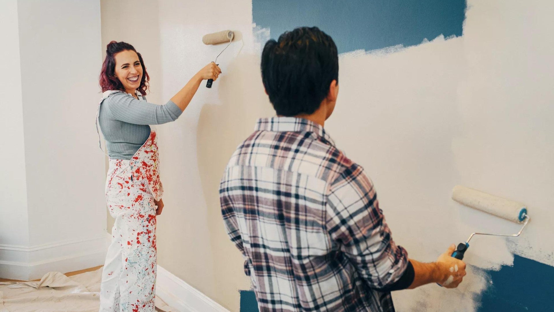 A couple painting a wall in their new home.