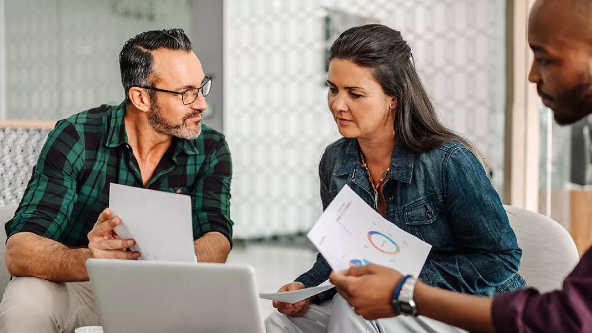 Three people discussing how mutual funds work in front of a laptop.